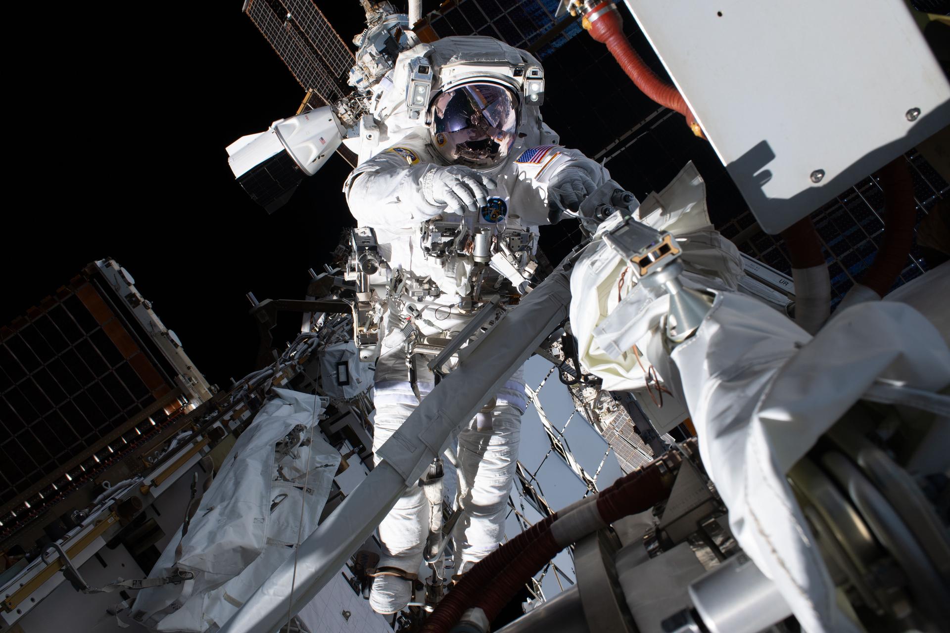 Anil Menon outside the International Space Station on his first spacewalk, August 6, 2026 — the configuration he returns to today. (NASA, Expedition 75)