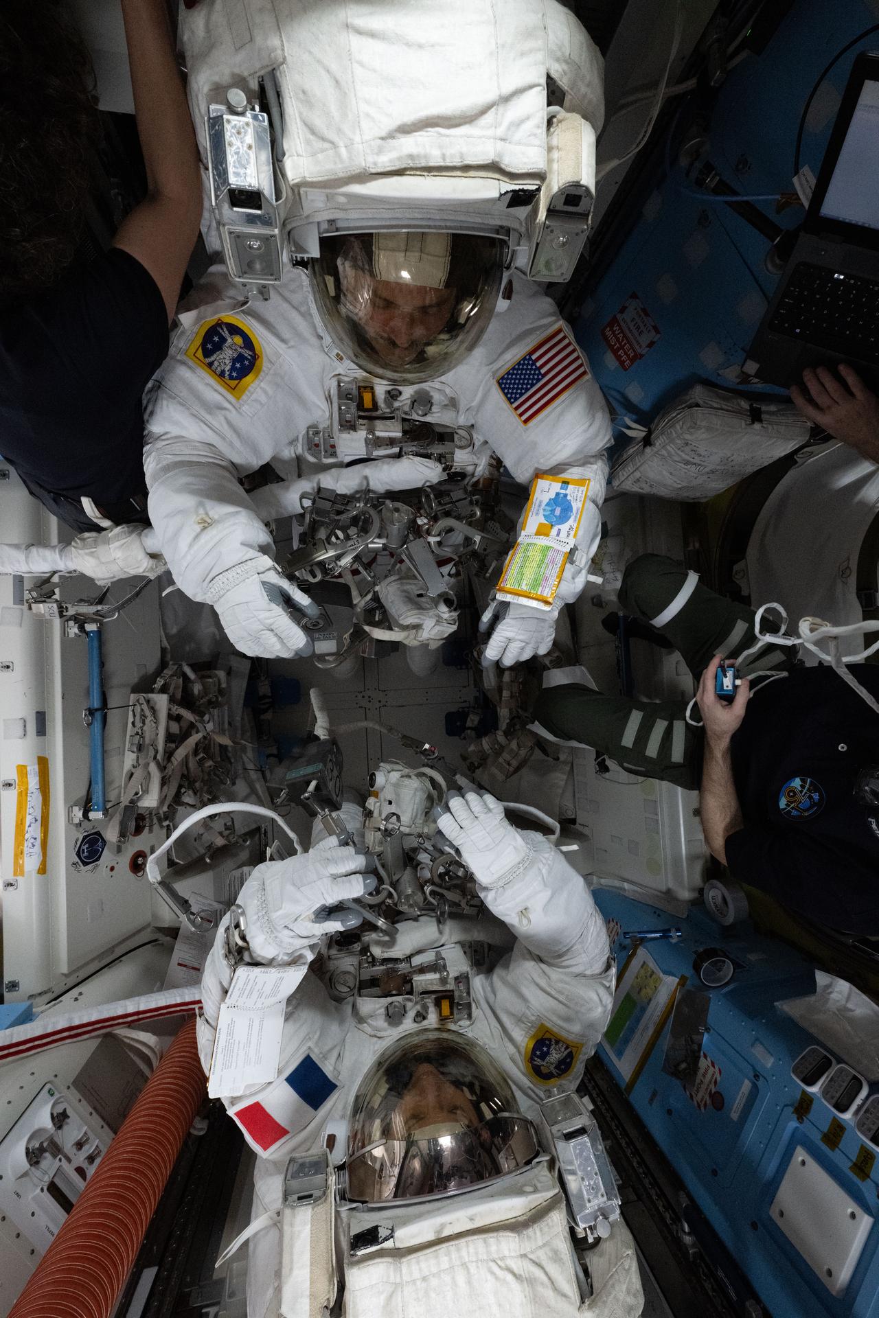 Anil Menon and Sophie Adenot suited up inside the Quest airlock before U.S. Spacewalk 97 on Aug. 18, 2026 — the same pair who will return outside on Aug. 25 to finish the antenna replacement. (NASA)