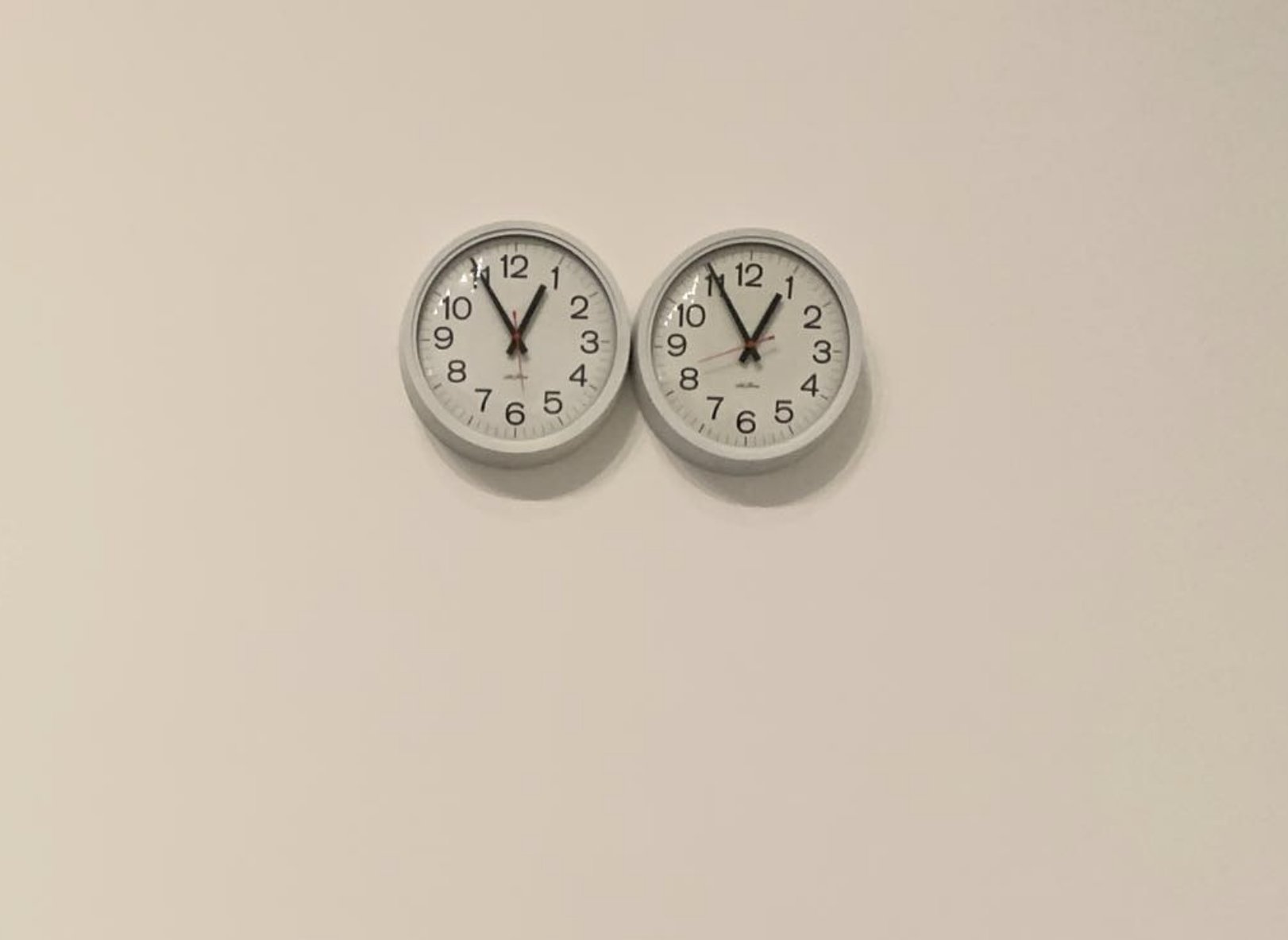 Felix Gonzalez-Torres, "Untitled" (Perfect Lovers), 1991. Two wall clocks mounted side by side at MoMA, intended to synchronize and inevitably drift apart over time. Two identical mechanisms on parallel tempos — the visual analogue of a substrate that ships on two clocks.